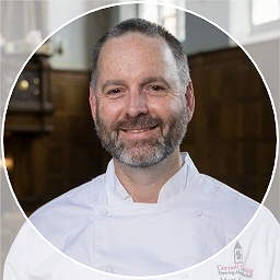 A smiling person wearing a chef coat