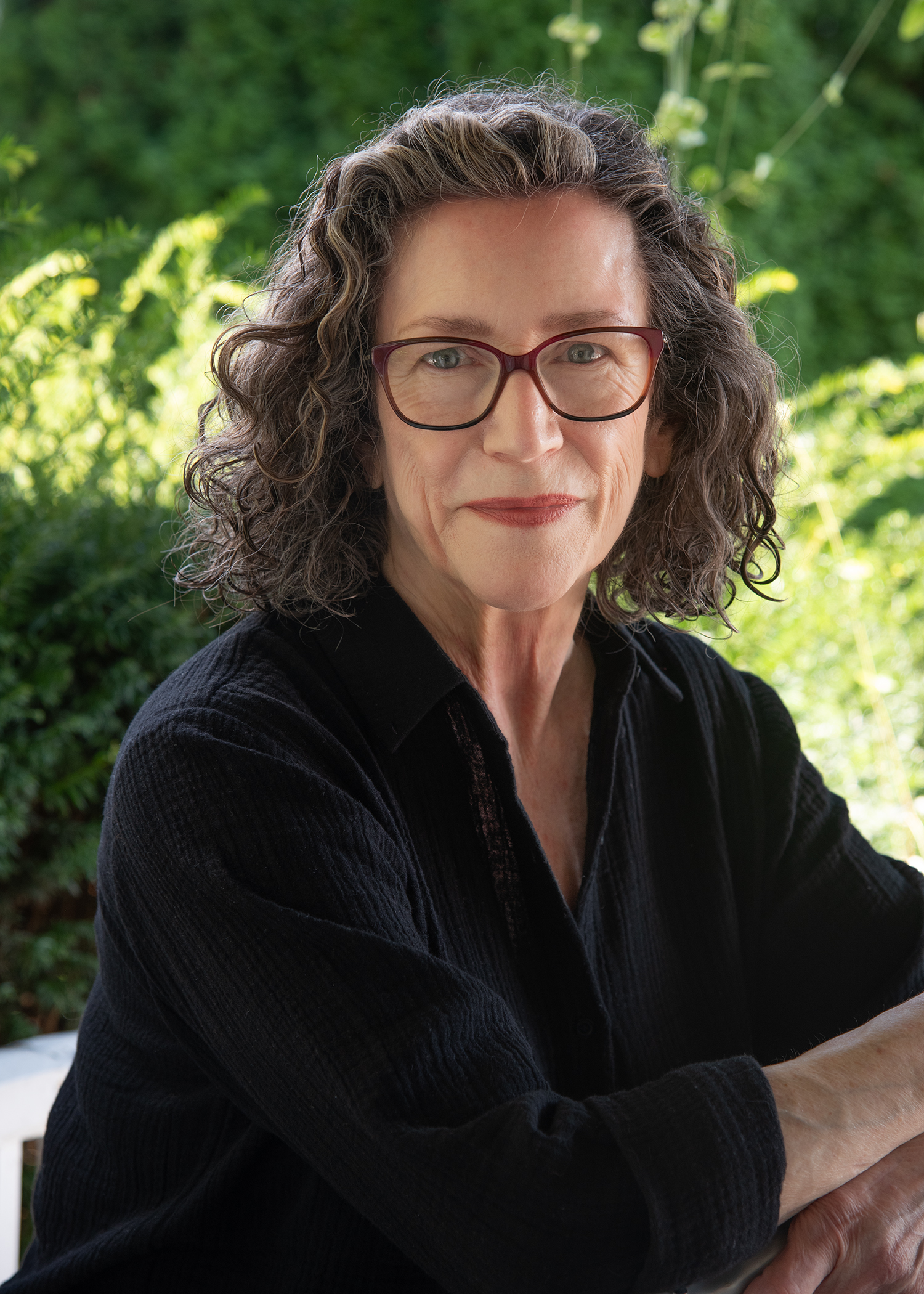 A person with a closed mouth smile looks at the camera from an outdoor setting.